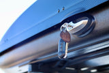 Key in lock of a textured black cargo box, commonly used on an RV rental, highlighting secure travel storage.