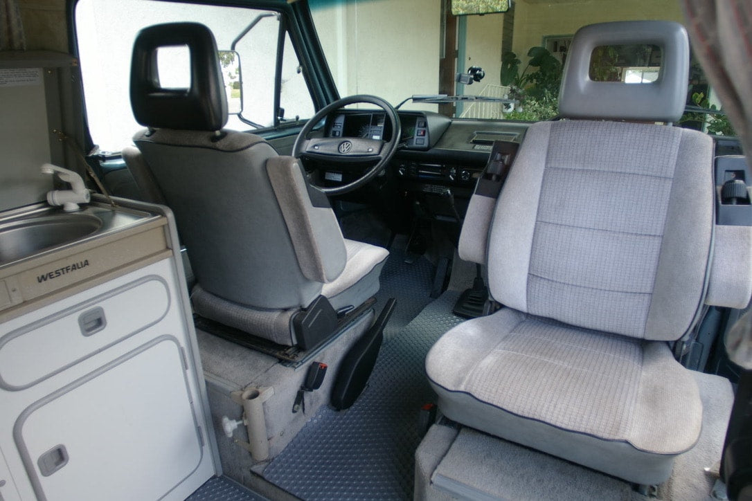  dual headlights.|Explore this VW Westfalia camper van RV rental interior. Features swivel seats — photo 7