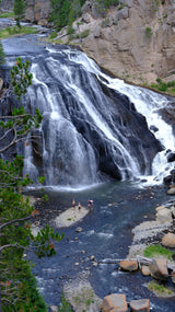 Majestic cascading waterfall and river with people exploring the base, a perfect scenic stop for your RV rental journey.