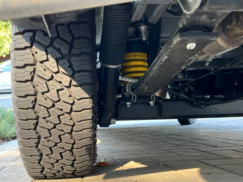 Underside view of an RV rental: robust tire, yellow suspension coil, and black shock, ready for adventure. — photo 7