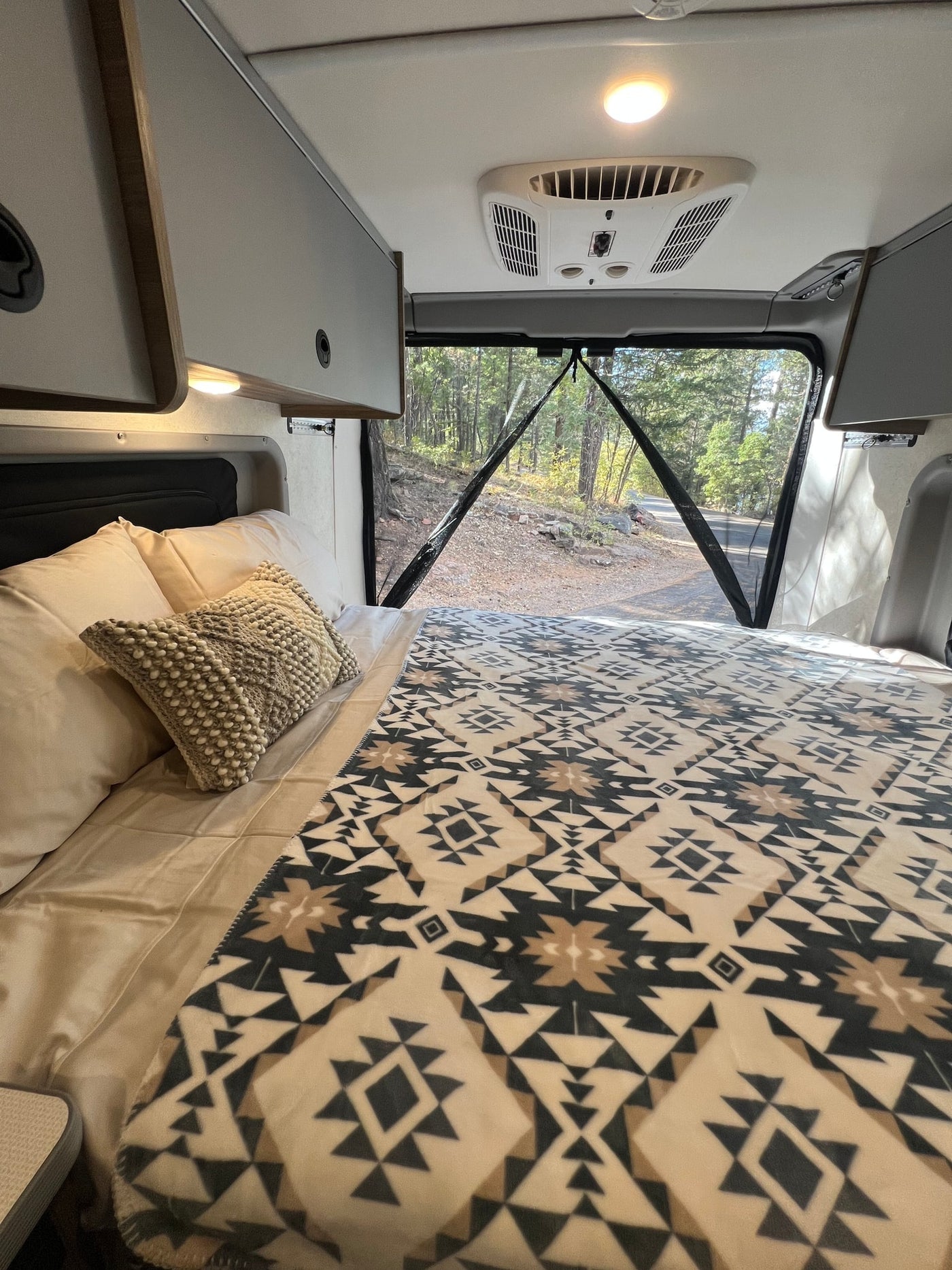  customized interior for your next road trip adventure.|RV rental interior: bed with patterned blanket — photo 13