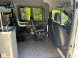 Spacious RV rental interior featuring versatile passenger seating, a compact sink, and control panel, ideal for road trips.