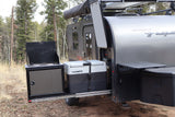 RV rental's outdoor kitchen featuring a Dometic fridge and stove, pulled out from the camper in a forest.