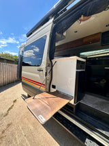 This rv rental offers a versatile outdoor workspace with a pull-out table and a glimpse into its modern camper interior.