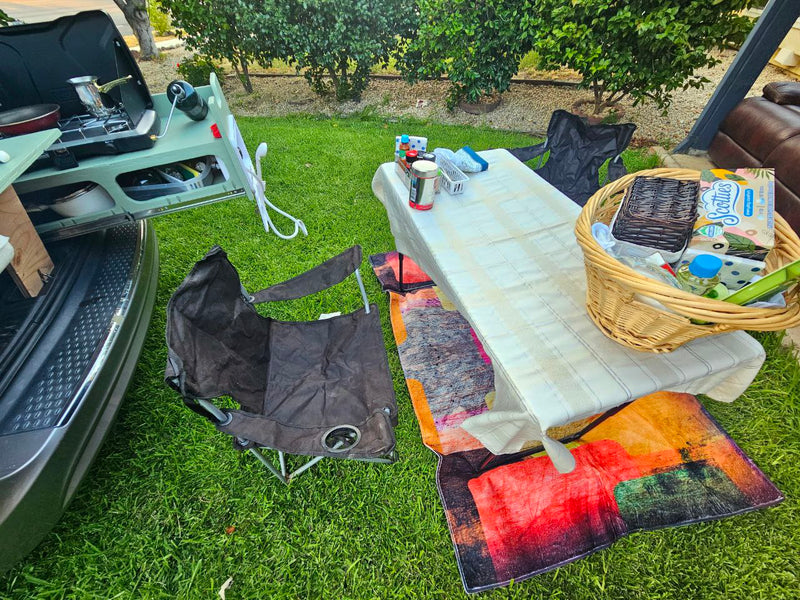RV rental outdoor kitchen and dining setup on grass with chairs & picnic basket. — photo 19