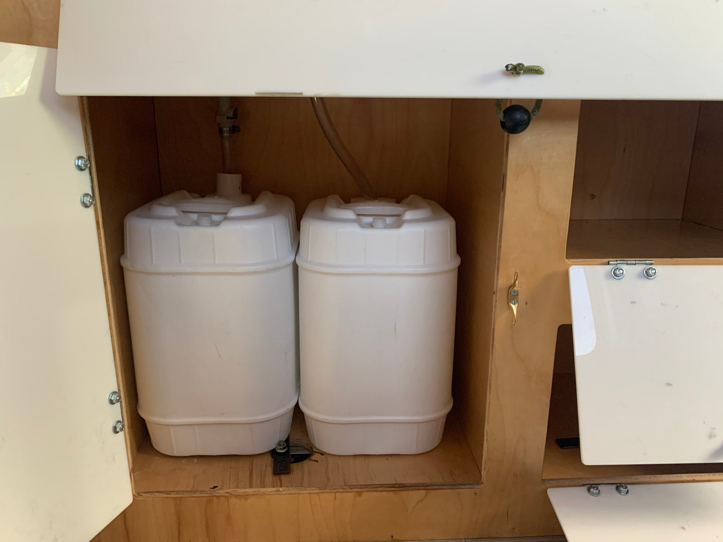 Two water tanks neatly stored in a compact cabinet, likely for fresh or grey water in an RV rental. Ideal for a self-contained trip.