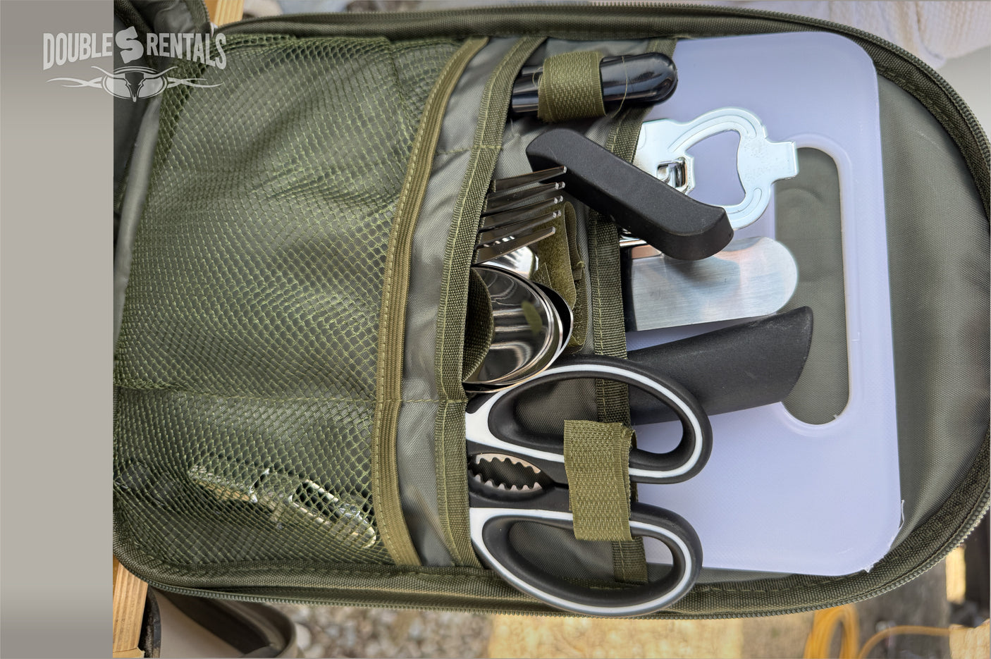 RV rental ready: This olive green camping kitchen set includes forks, spoons, bottle opener, knife, scissors, and a cutting board.