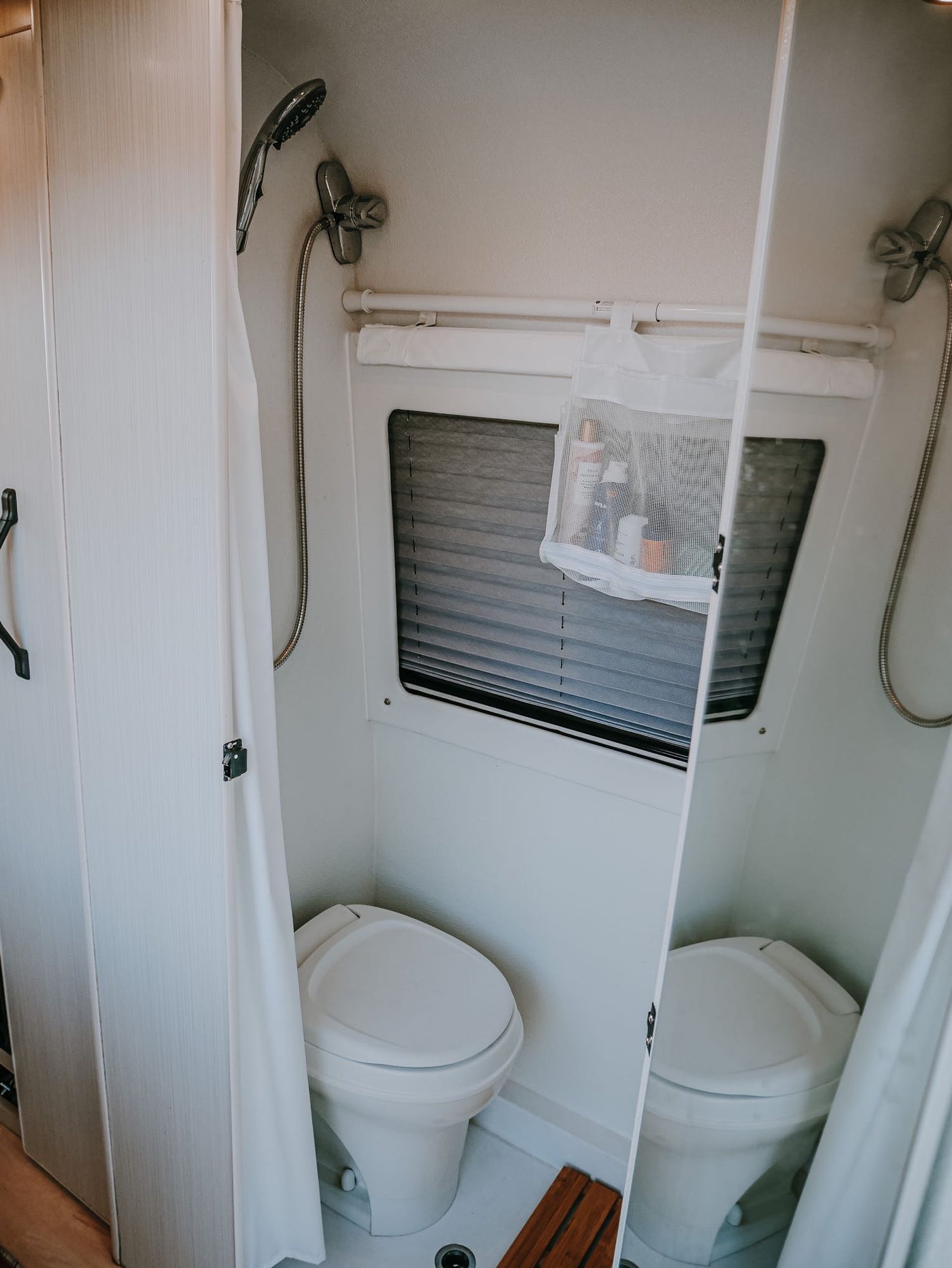  and outdoor views through two windows. Perfect for glamping trips.|Relaxing RV rental view! Inside a camper looking out at two blue chairs — photo 13