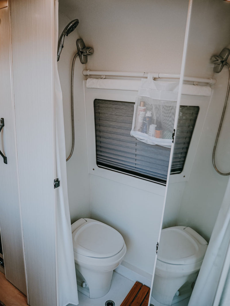  and outdoor views through two windows. Perfect for glamping trips.|Relaxing RV rental view! Inside a camper looking out at two blue chairs — photo 13