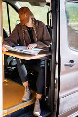 Planning your next adventure! Woman studies a map inside a cozy RV rental van, ready for the open road.