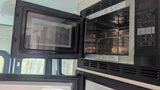 RV rental interior: Open microwave/convection oven, showing its metal rack and digital controls, ready for cooking.
