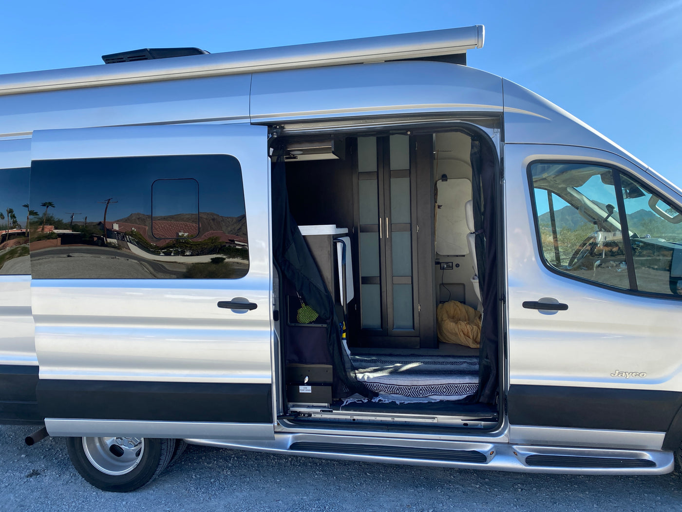 Silver Jayco RV rental with its side door open, revealing the interior, a cooler, cabinets, and a patterned rug. — photo 11