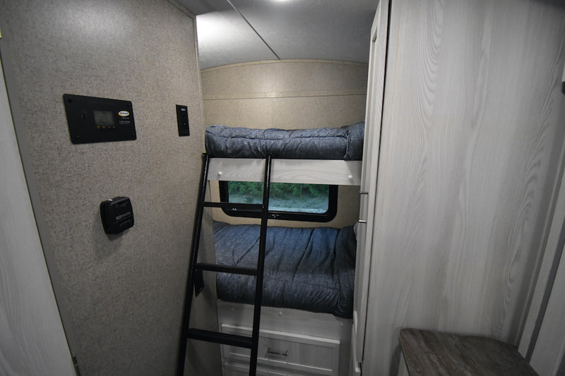 Cozy RV rental bedroom with bunk beds, a ladder, window view, and system controls on the wall for a comfortable stay. — photo 12