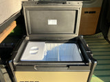 ARB fridge freezer open in an RV rental, showing internal compartments for food storage on your van life adventure.