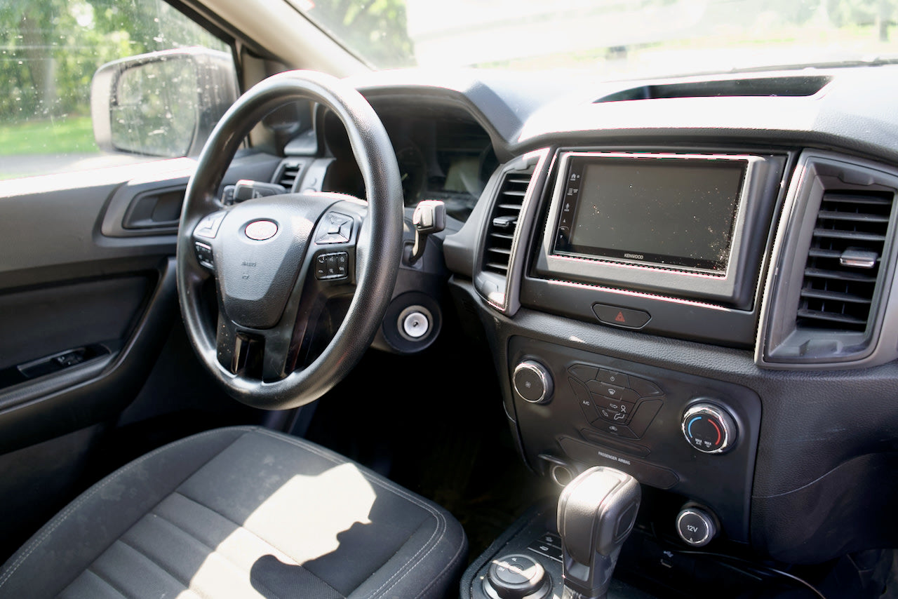 Driver's view inside an RV rental vehicle, showing the steering wheel, Kenwood screen, and dashboard controls.