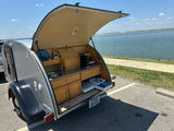 This RV rental teardrop trailer shows its open rear galley with a fully equipped kitchen setup, perfect for lakeside camping adventures.
