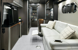 Inside a sleek **RV rental**: modern kitchen, white leather sofa, and TV create a luxurious travel experience.
