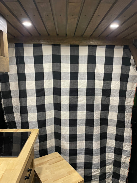 RV rental interior featuring a wood plank ceiling, checkered curtain, and kitchenette with cooktop.
