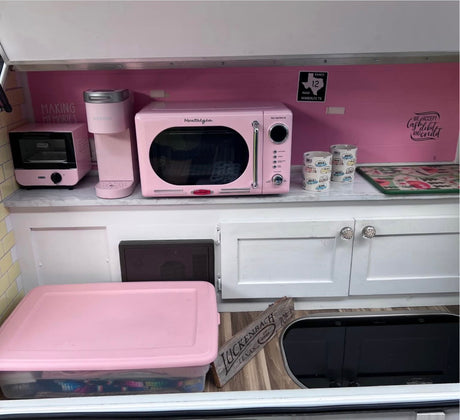 Cozy pink retro RV rental kitchen, featuring a microwave, Keurig, and toaster oven for making travel memories.