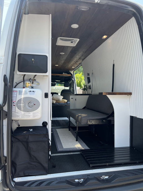 This RV rental's interior boasts a Bosch water heater, a convertible bench, and a rustic wood plank ceiling.