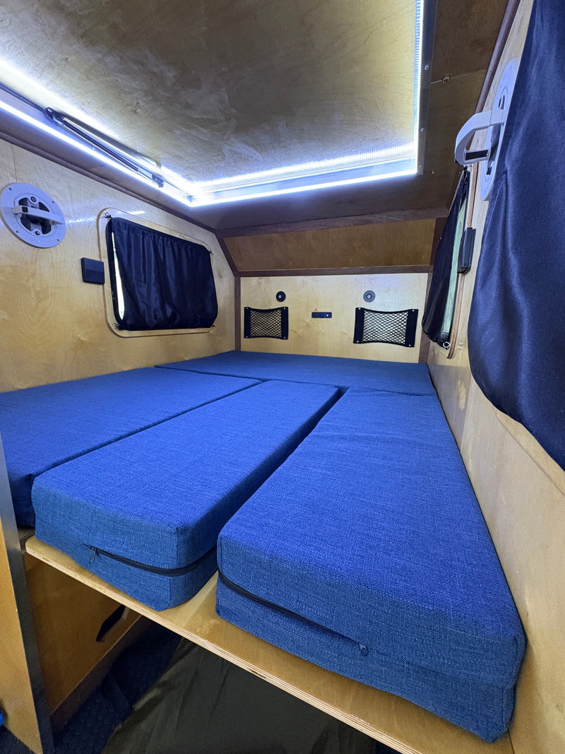 Interior of an RV rental: blue modular bed setup, bright LED ceiling lights, and wooden paneling. — photo 4