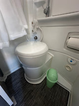 This RV rental features a compact, integrated wet bath with a toilet, shower, curtain, and essential amenities.