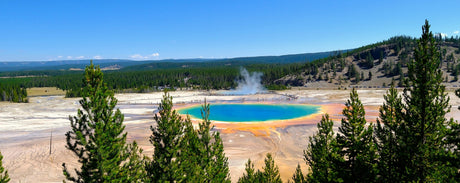 Yellowstone's vibrant Grand Prismatic Spring, with steam and visitors on boardwalks. Explore this natural wonder with an RV rental trip.