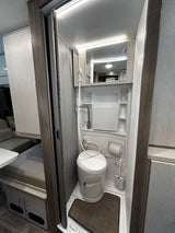 Compact RV rental wet bath featuring a toilet, shower, and sink. This functional space is ideal for travel convenience.