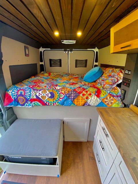 Step inside this custom rv rental camper van: a vibrant bed, efficient kitchen with Dometic fridge, and cozy seating await. — photo 12