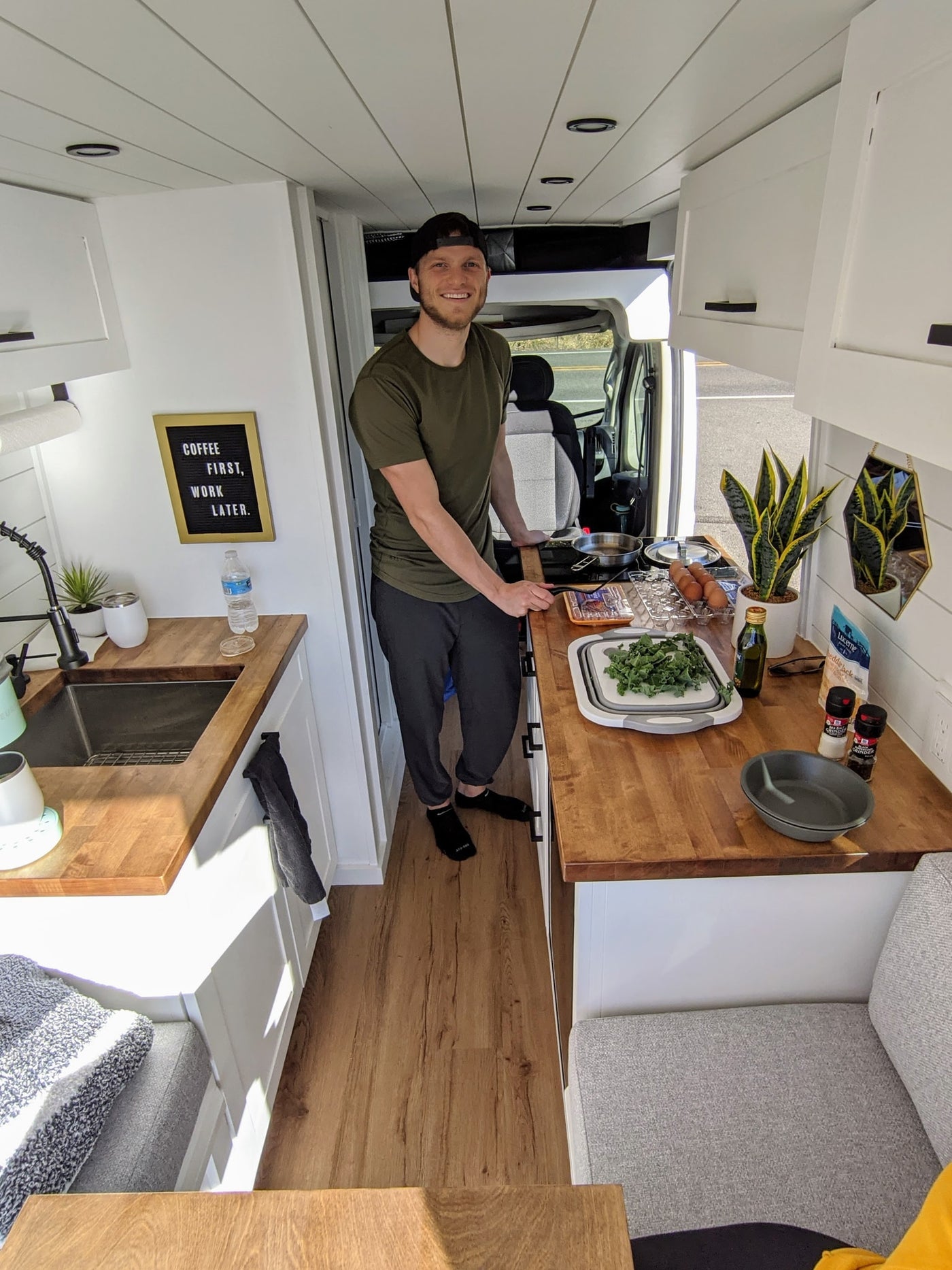 Man cooks in his compact, well-equipped RV rental kitchen. Modern interior with wood accents, perfect for van life adventures. — photo 18