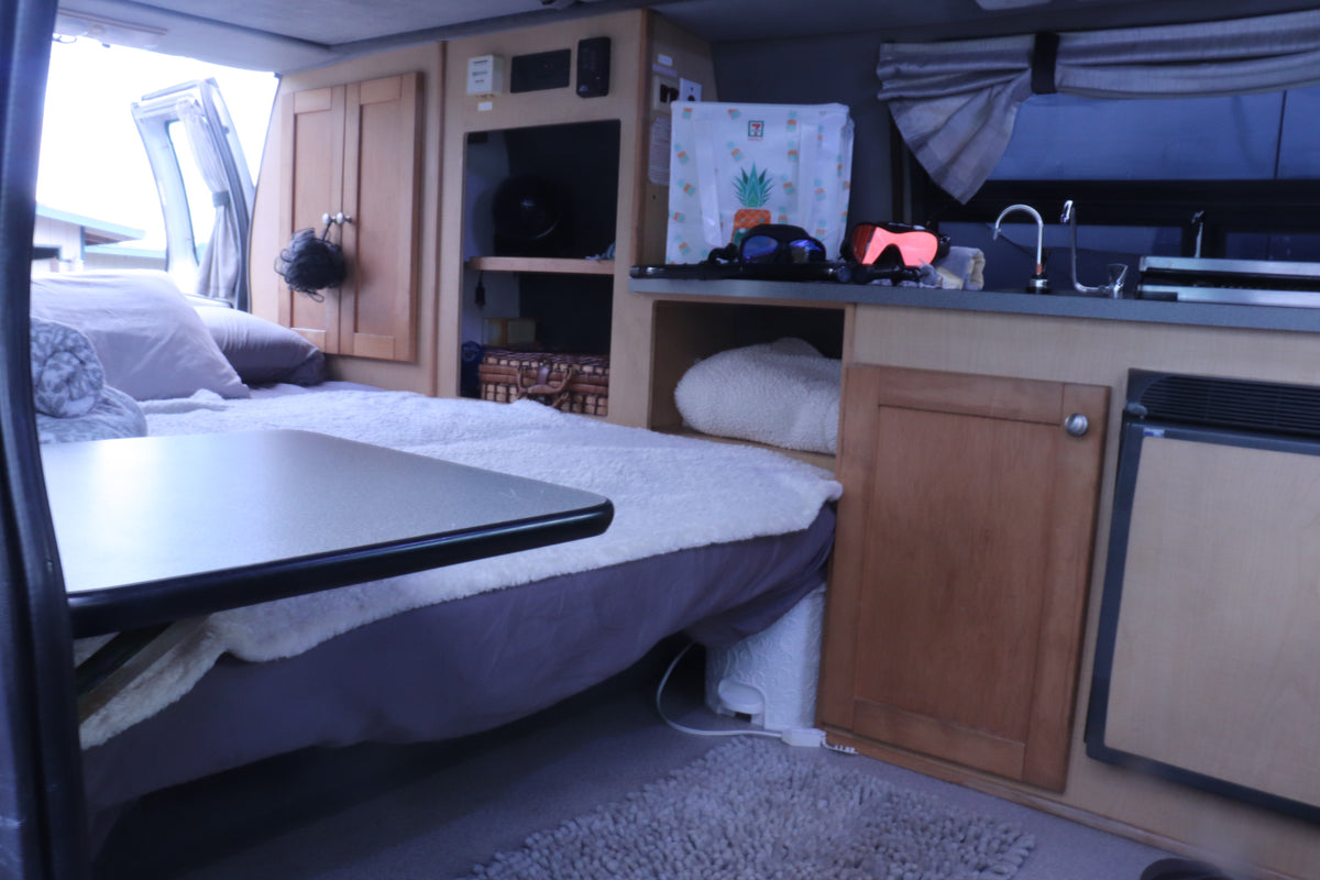 Cozy RV rental interior showcasing a bed, kitchen, cabinets, and a table. Perfect for mobile adventures. — photo 14