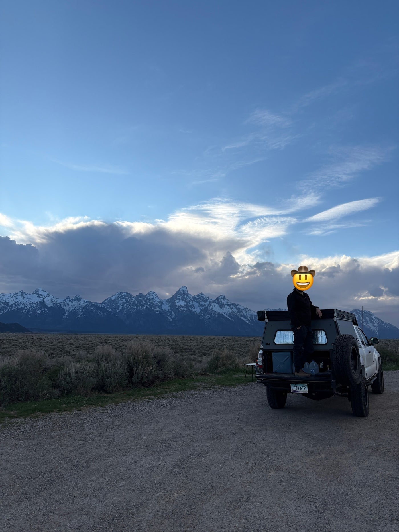 Person in a truck camper overlooking snow-capped Grand Teton mountains & vast plains. Perfect RV rental for an overland adventure! — photo 8