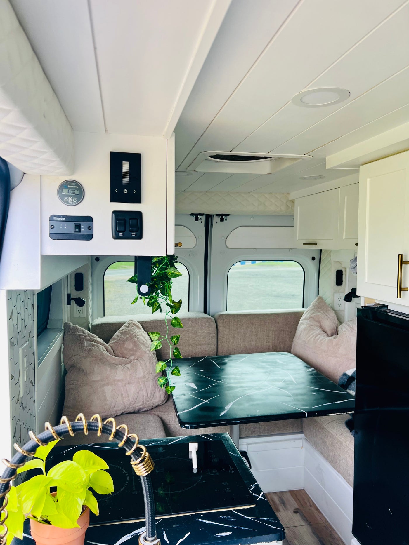 Inside a modern RV rental: a bright living area with a dinette, kitchen boasting marble-patterned counters, and accessible control panel. — photo 11