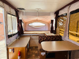 Spacious RV rental pop-up camper interior with beds, dinette, sink, and ample counter space for travel.