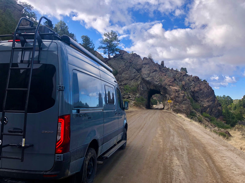 Experience adventure with an RV rental! A grey Mercedes Sprinter van on a dirt road approaches a majestic natural rock tunnel. — photo 2