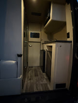 Step inside this RV rental, showcasing a compact kitchen, comfy seating area, and wood-look flooring.