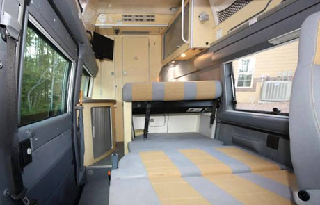 Explore this cozy RV rental interior with its flexible seating, convertible bed, compact kitchen, and scenic windows.