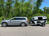A silver SUV tows a grey Sunray Sport compact travel trailer RV, ready for an RV rental adventure.
