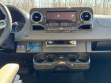Detailed RV rental dashboard: steering wheel, infotainment screen, climate controls, custom power & refrigerator buttons.