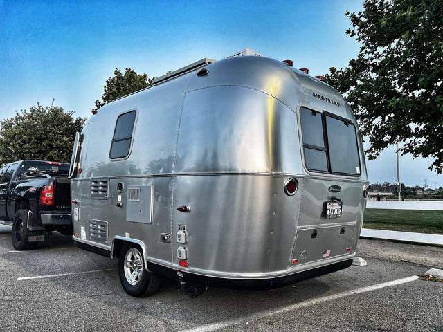 Silver Airstream travel trailer, perfect for an rv rental, hitched to a black pickup truck, ready for camping.