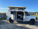 Explore in a white 4x4 pop-top camper van, doors open revealing the interior. Your ultimate rv rental adventure awaits!