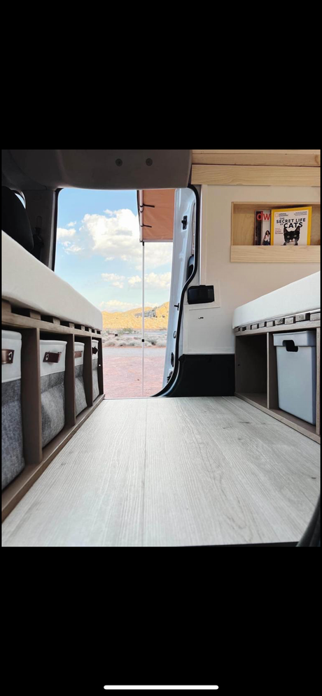 Cozy rv rental interior with storage & comfy bed, showcasing a stunning desert view from the open back door.