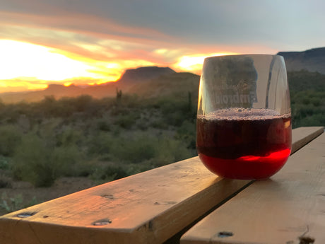 Enjoying a vibrant desert sunset with red wine on a wooden deck. Perfect end to an RV rental day.