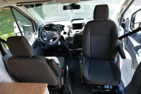 View inside an RV rental van: front cabin with driver's and passenger seats, dashboard, and Ford steering wheel.