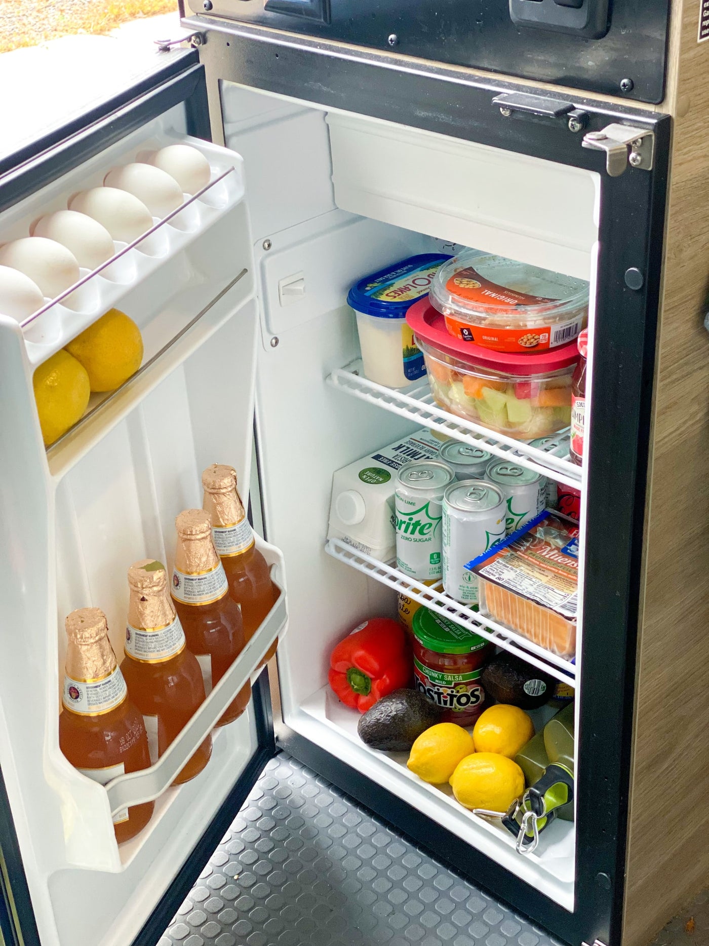 RV rental fridge stocked with essentials: eggs, drinks, fruit, cheese, and veggies for easy meals on the go. — photo 15
