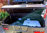 Open StowAway cargo box on an RV rental, holding a cooler and camping gear for convenient travel storage.
