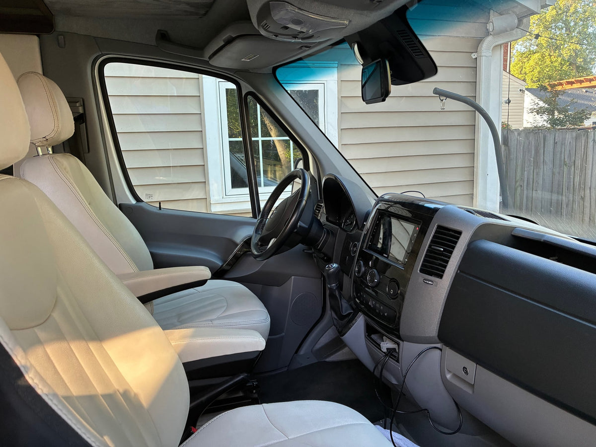  and windows revealing green outdoor views. Travel comfort.|Modern RV rental interior with a large smart TV displaying Roku apps — photo 6