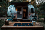 Relax in this Airstream rv rental! Parked on a private deck with chairs, fire pit, and beautiful nature backdrop.