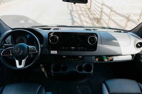 Inside a modern RV rental: A detailed view of the Mercedes-Benz dashboard, steering wheel, and cabin controls.