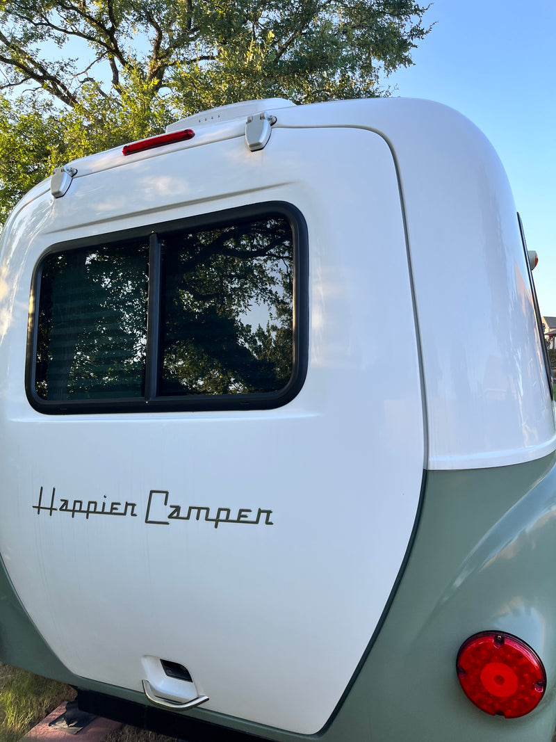 Detailed rear view of a white Happier Camper RV rental, showing its window, red taillight, and green lower body. — photo 10